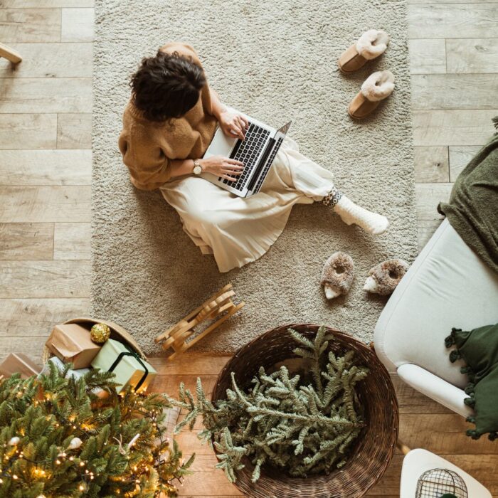 Small business owner on a laptop with holiday decor all around her as she refines her holiday SEO.