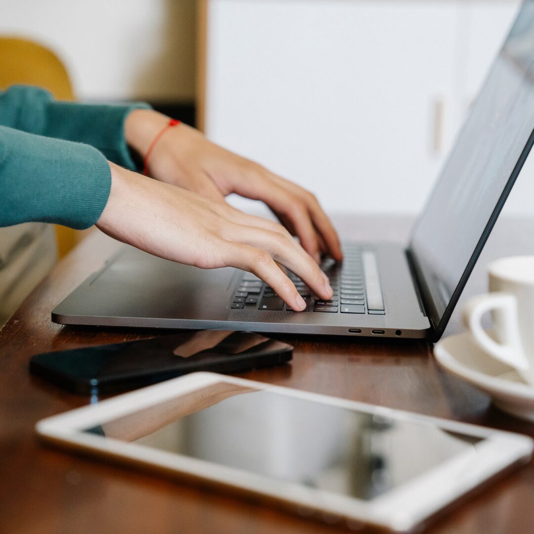 Entrepreneur at a desk, looking at a website on a laptop, possibly with notes or compliance checklist.