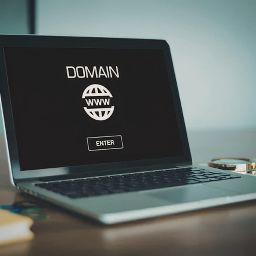 Laptop on a desk with a dark screen on with the word Domain on the screen.